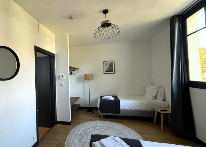 Suite familiale n°03 de l’hôtel La Réserve de Brive, composée de deux chambres avec deux lits doubles et un lit simple, décoration chaleureuse et salle de bain avec baignoire.