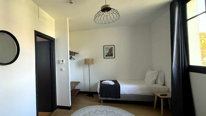 Suite familiale n°03 de l’hôtel La Réserve de Brive, composée de deux chambres avec deux lits doubles et un lit simple, décoration chaleureuse et salle de bain avec baignoire.